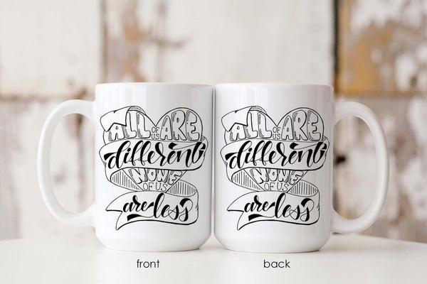 15oz white ceramic mug with hand lettered illustrated design that says all of us are different none of us are less showing front and back of mug