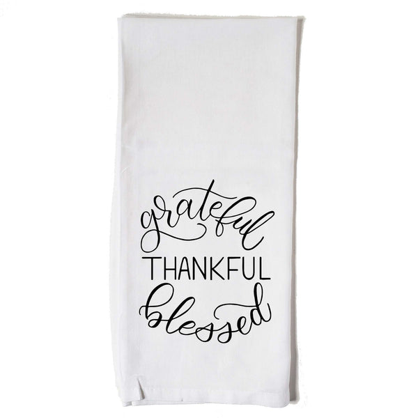 White floursack towel with black hand illustrated design that says grateful thankful blessed