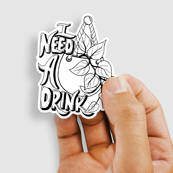 3" black and white illustrated hand lettered vinyl sticker says I need a drink with an illustrated hanging pothos plant shown with a woman's hand holding the sticker