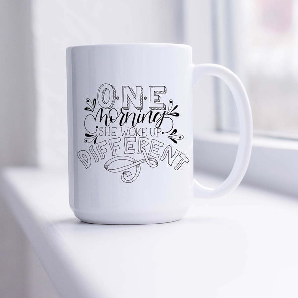 15oz white ceramic mug with hand lettered illustrated design that says I will become all that I was created to be shown in a sunny window