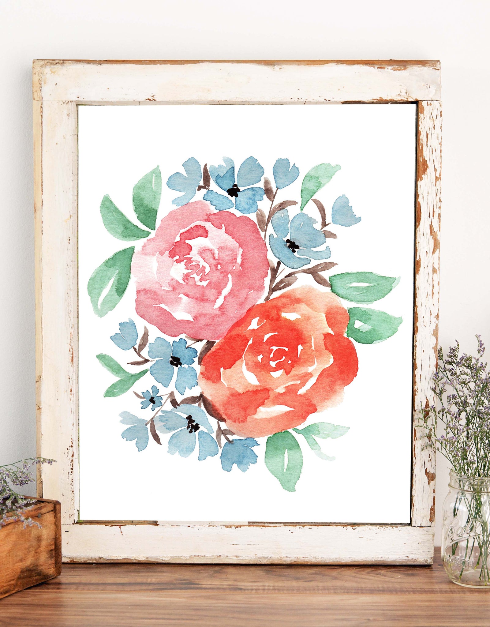 Watercolor wall art print with coral and rust colored roses, little muted blue accent flowers and green leaves shown in a chippy old white frame sitting on a shelf