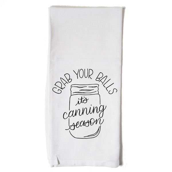 White floursack kitchen towel with black hand lettered illustrated design that says Grab your balls it's canning season with a mason jar doodle