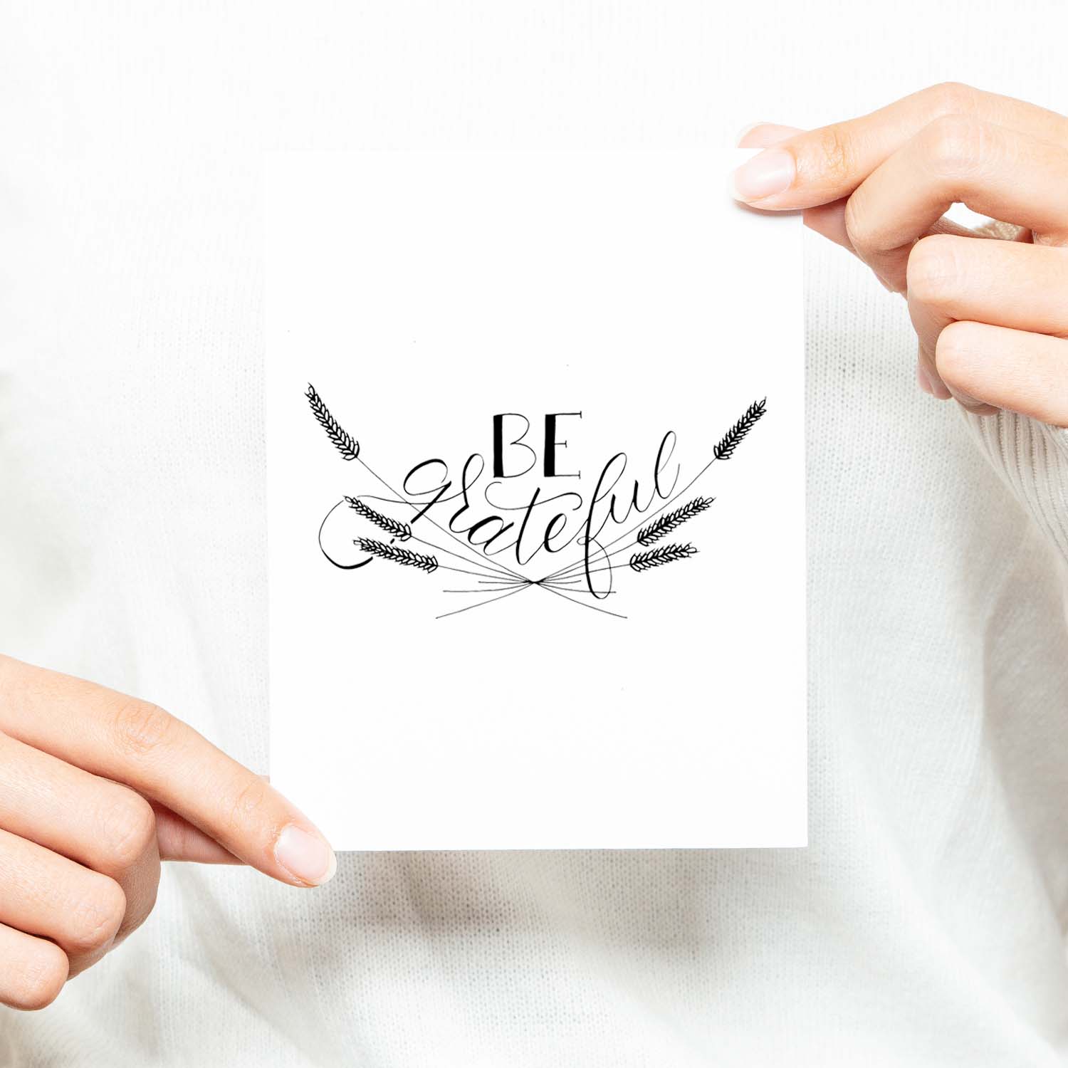 Be Grateful A2 Greeting Card, black hand lettered design with wheat illustrations on a folded white card shown with a woman in a white sweater holding card