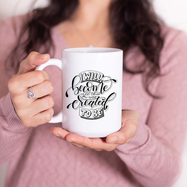 15oz white ceramic mug with hand lettered illustrated design that says I will become all that I was created to be shown with a woman holding the mug