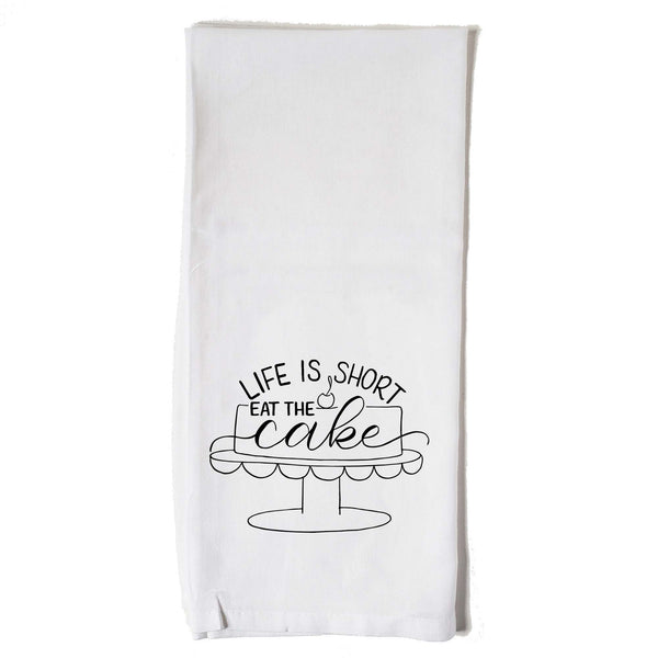 White floursack towel with black hand lettered illustrated design that says Life is short eat the cake with a cake on a stand doodle