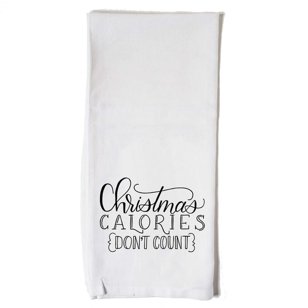 White floursack towel with black hand lettered illustrated design that says Christmas calories don't count