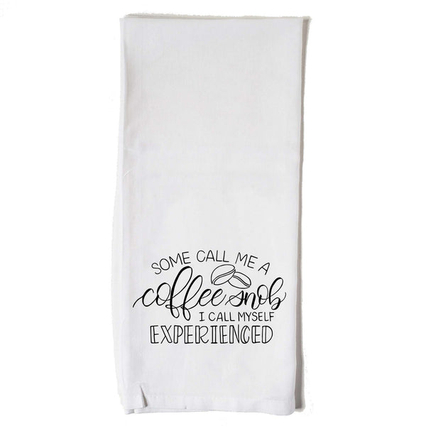 White floursack towel with black hand lettered illustrated design that says Some call me a coffee snob, I call myself experienced with coffee bean doodles