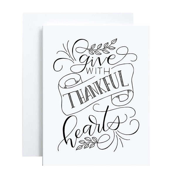 Give with thankful hearts hand lettered greeting card design in black on a folded white card with A2 envelope