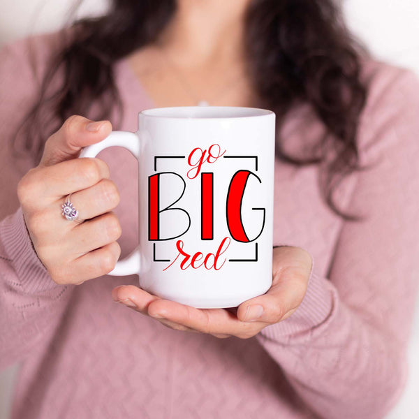 15oz white ceramic mug with hand lettered illustrated design that says Go Big Red shown with a woman holding the mug