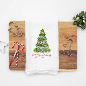 Floursack Kitchen Tea Towel with a watercolor Christmas tree with colorful lights that says home for the holidays