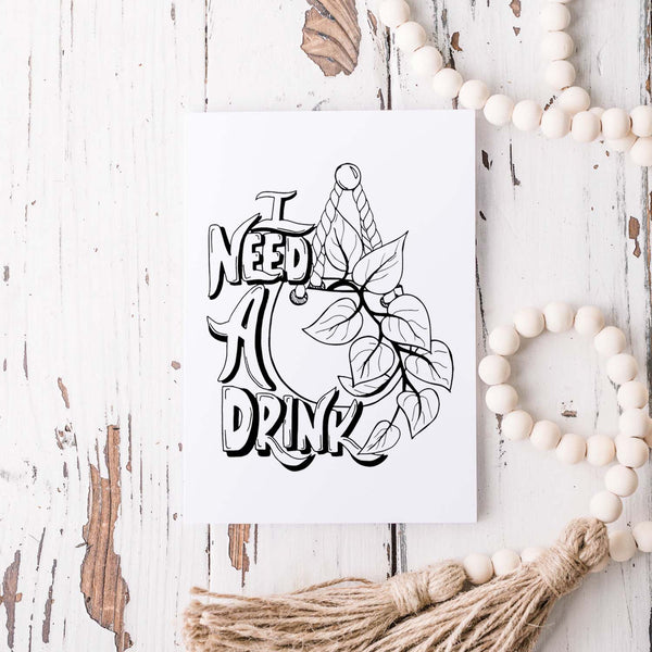 I need a drink potted pothos plant black and white illustrated greeting card on a white folded card with A2 envelope shown on a wooden rustic table and white wooden bead garland