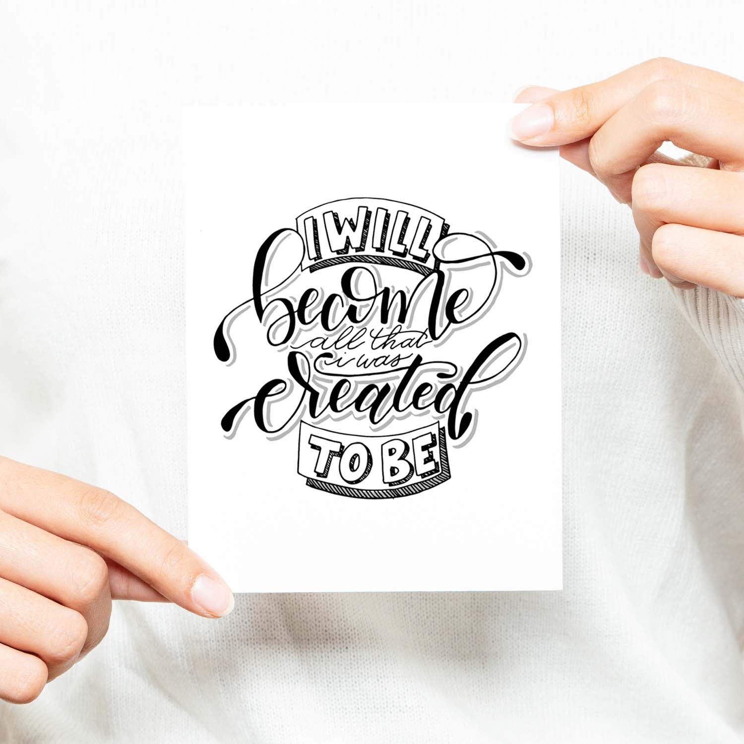 I will become all that I was created to be black and white hand lettered greeting card on a white folded card with A2 envelope shown with a woman in a white sweater holding card