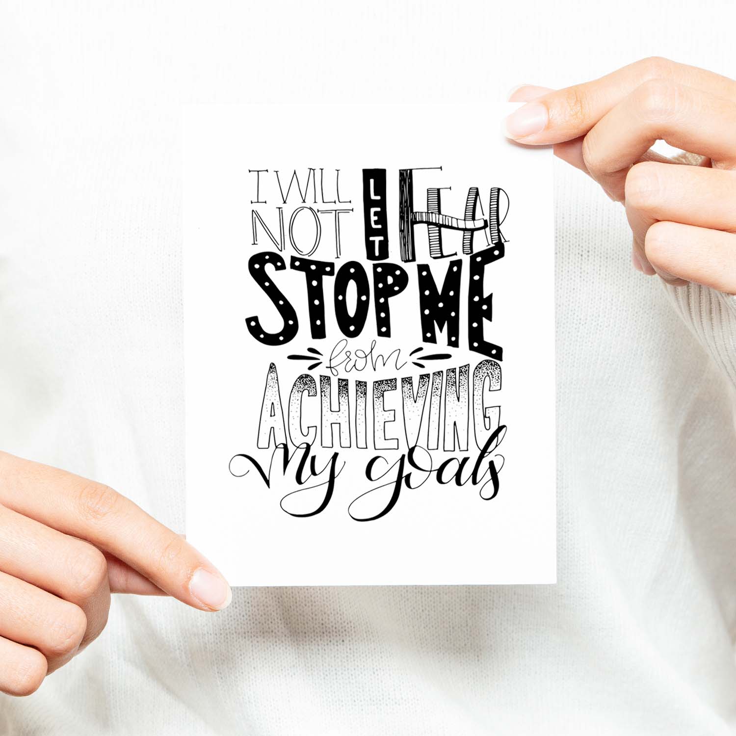 I will not let fear stop me from achieving my goals hand lettered black and white greeting card on a white folded card with A2 envelope shown with a woman in a white sweater holding card