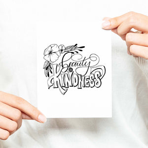 Beauty is kindness hand lettered and illustrated black and white greeting card on a folded white card with an A2 envelope shown with a woman in a white sweater holding card