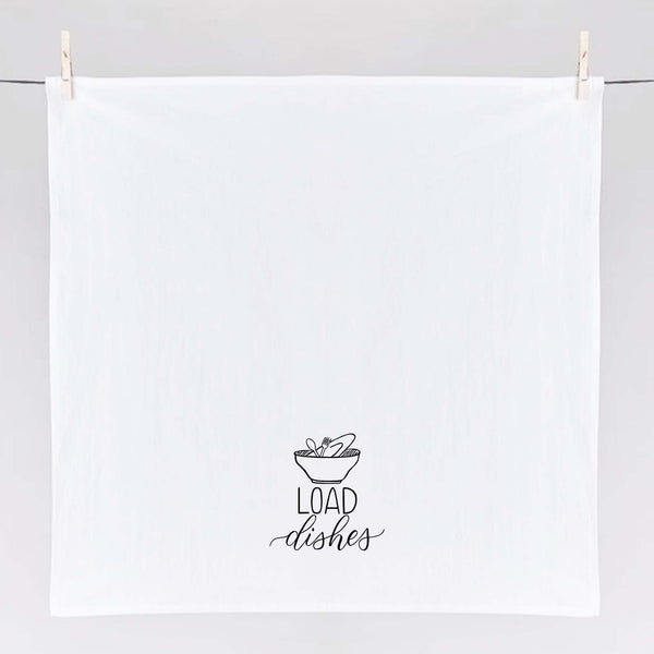 White floursack towel with black hand lettered illustrated design that says Load dishes with pile of dirty dishes doodles shown unfolded and hanging from clothes pins