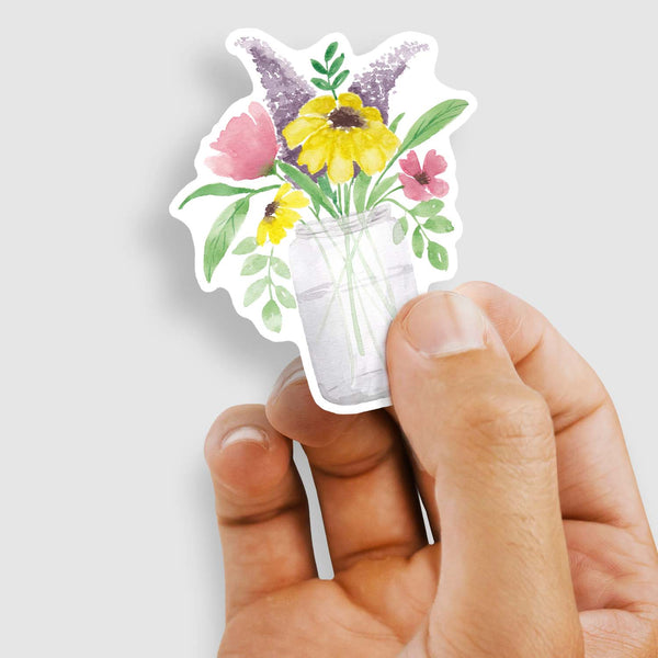 3" vinyl sticker of watercolor mason jar full of wild summer flowers shown with a woman's hand holding the sticker