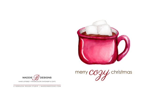 Watercolor Christmas greeting card with a watercolor painted red mug full of hot cocoa and heaping with marshmallows that says merry cozy christmas laying open flat to show front and back of card