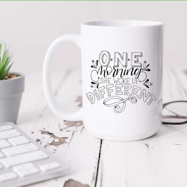 15oz white ceramic mug with hand lettered illustrated design that says I will become all that I was created to be shown sitting on a white desk with plant and keyboard and glasses