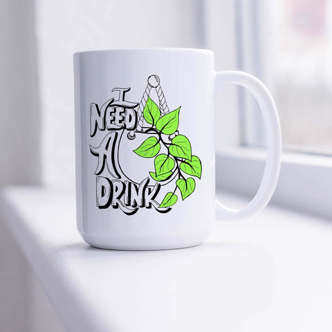 15oz white ceramic mug with hand lettered illustrated design that says I need a drink with an illustration of a pothos plant with green leaves in a hanging pot shown sitting in a sunny window