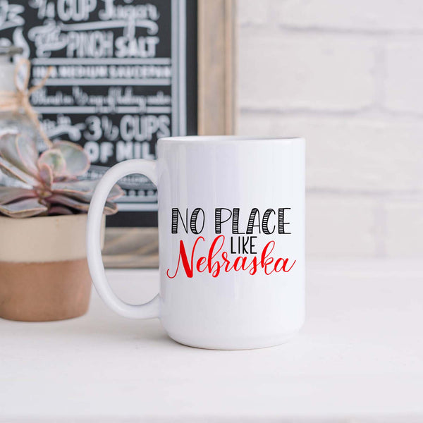 15oz white ceramic mug with hand lettered illustrated design that says No Place Like Nebraska shown in a kitchen