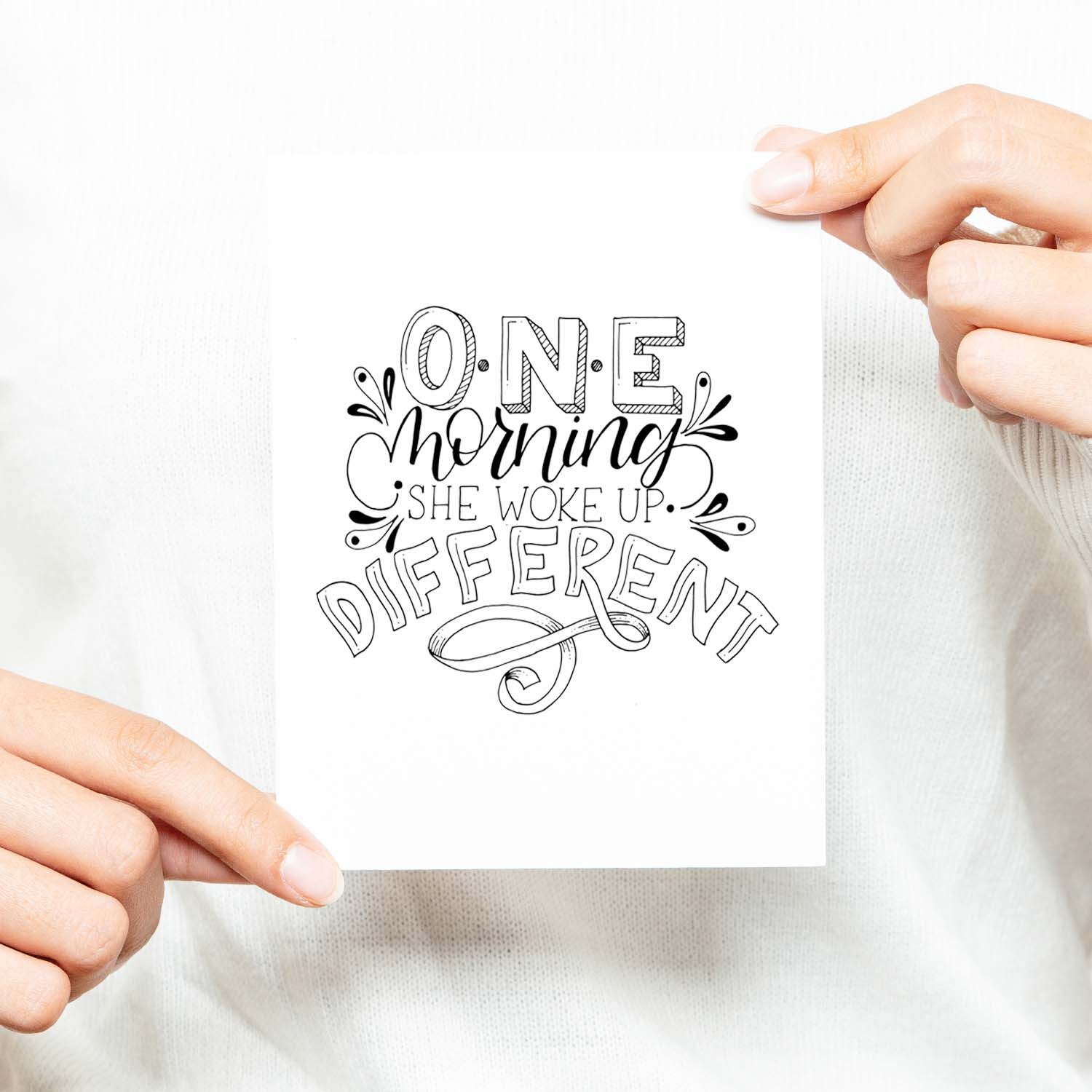 one morning she woke up different hand lettered and illustrated black and white greeting card with A2 envelope shown with a woman in a white sweater holding card