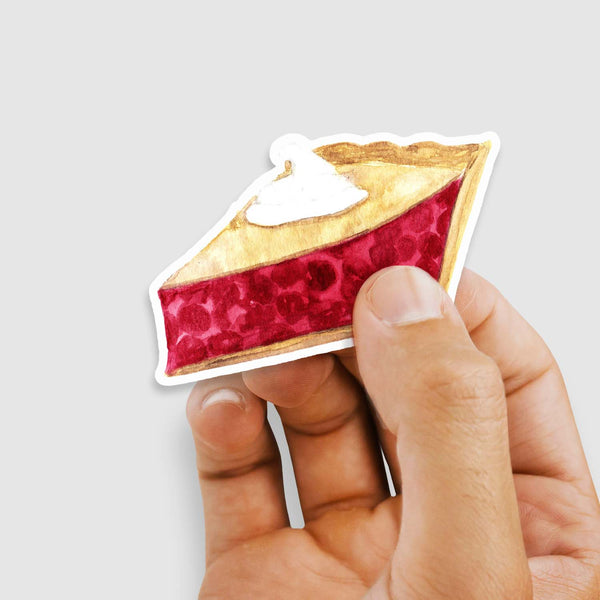 3" vinyl sticker of a watercolor painted slice of cherry pie with whipped cream on top shown with a woman's hand holding the sticker