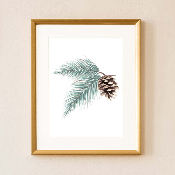 Watercolor painting of evergreen branches and pinecone shown hanging on a wall in a gold frame