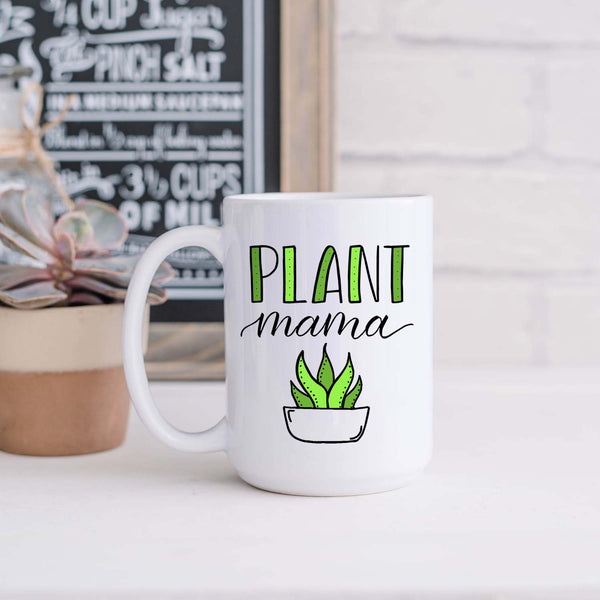 15oz white ceramic mug with hand lettered illustrated design that says Plant mama with the illustration of a succulent with green leaves shown sitting in a kitchen