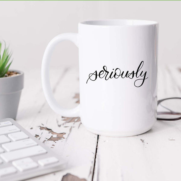 15oz white ceramic mug with hand lettered illustrated design that says seriously shown sitting on a white office desk
