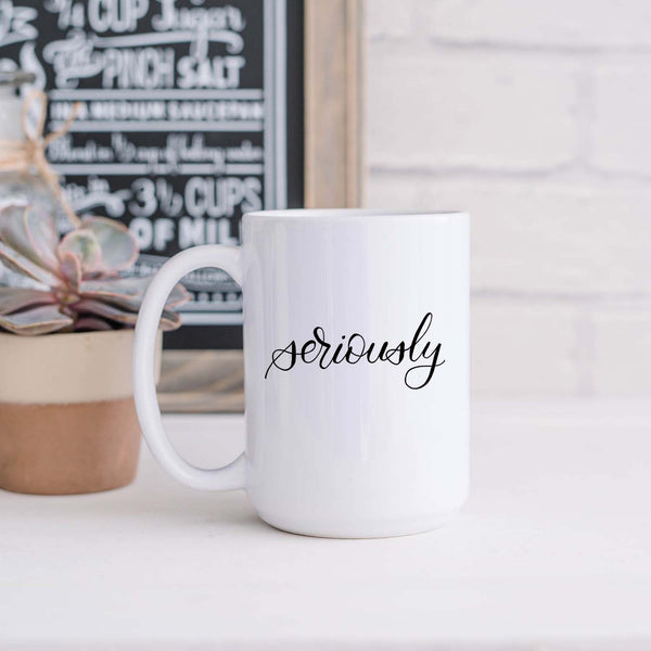 15oz white ceramic mug with hand lettered illustrated design that says seriously shown sitting in a kitchen