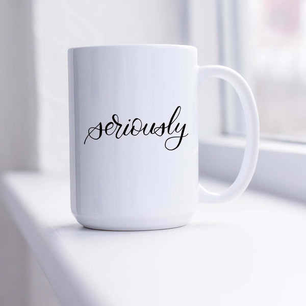 15oz white ceramic mug with hand lettered illustrated design that says seriously shown sitting in a sunny window