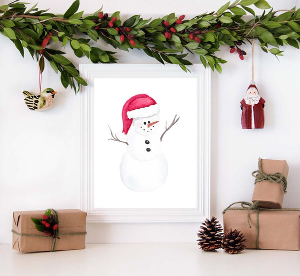 Watercolor painting of a chubby snowman wearing a santa hat shown in a white frame surrounded by christmas decorations