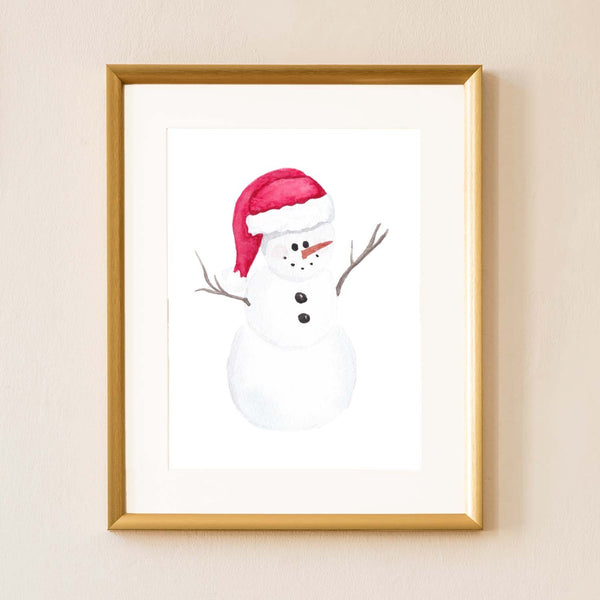 Watercolor painting of a chubby snowman wearing a santa hat shown hanging on a wall in a gold frame