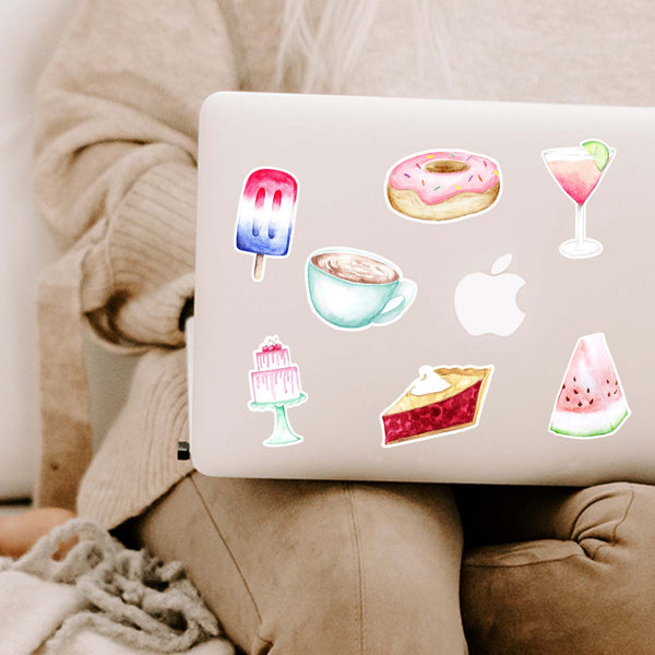 Collection of watercolor painted food stickers on a MacBook including a popsicle, donut, cocktail, coffee mug, cake, cherry pie and watermelon
