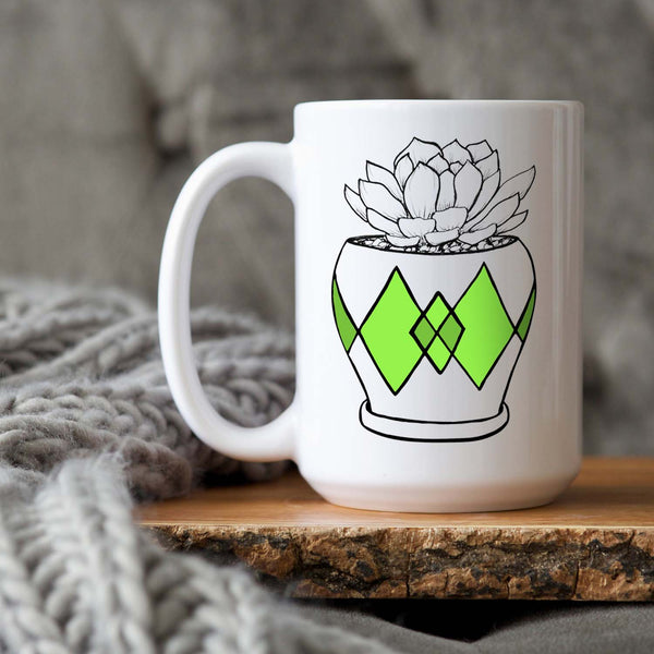 15oz white ceramic mug with hand lettered illustrated design of a succulent plant in a pot with green diamond pattern shown sitting on a wood tray with a grey knit blanket