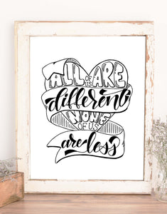hand lettered wall art design in black and white that says all of us are different none of us are less with an illustration of a heart and winding ribbon shown in a rustic frame on a shelf with accessories