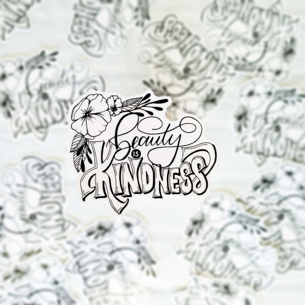 Hand lettered illustrated 3" vinyl sticker that says beauty is kindness with floral illustration in black and white