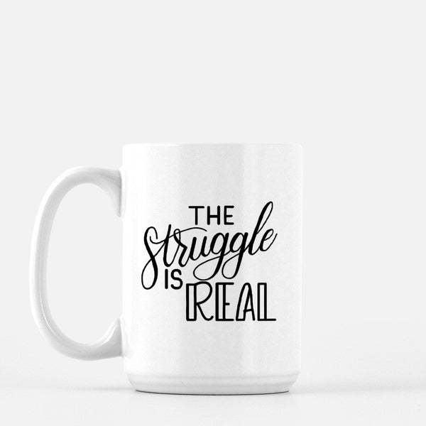 15oz white ceramic mug with hand lettered illustrated design that says the struggle is real