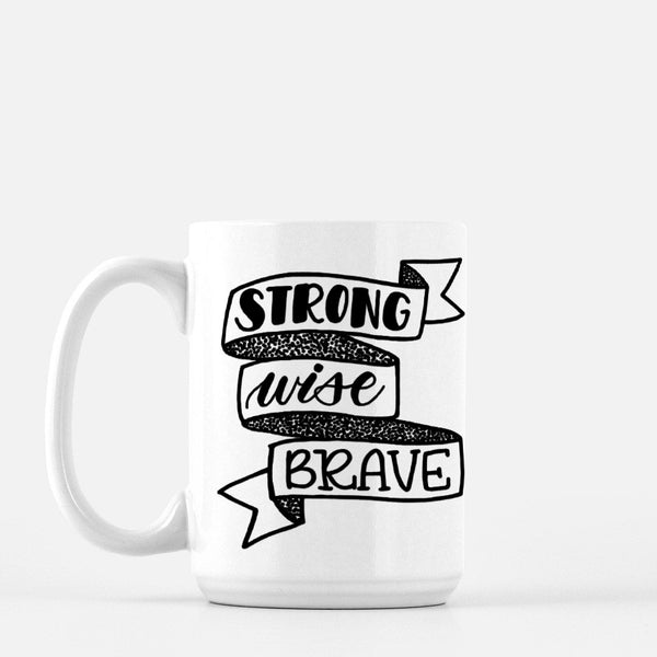 15oz white ceramic mug with hand lettered illustrated design that says strong wise brave inside a ribbon illustration