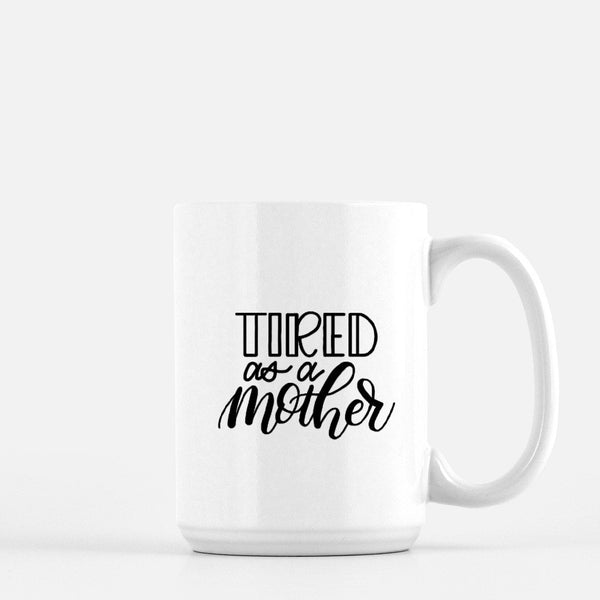 15oz white ceramic mug with hand lettered illustrated design that says tired as a mother