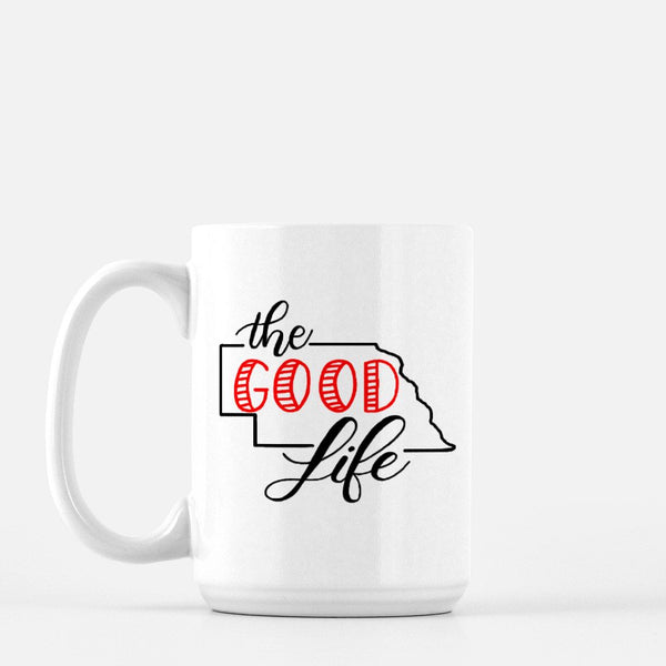 15oz white ceramic mug with hand lettered illustrated design that says The Good Life with the outline of the state of Nebraska