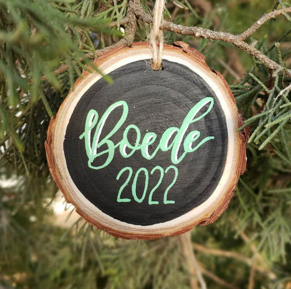 Hand painted rustic wood slice ornament with personalized first name in hand lettering and the year